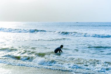 Chennai, Tamil Nadu, Hindistan - 02.07.2025: Okyanusta bir adam bir şey arıyor. Su mavi ve gökyüzü berrak. Chennai 'de.