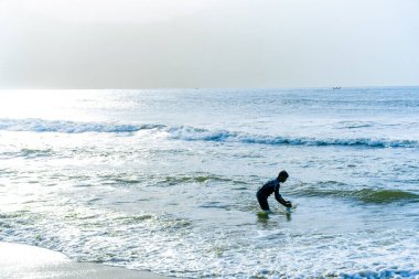 Chennai, Tamil Nadu, Hindistan - 02.07.2025: Okyanusta bir adam bir şey arıyor. Su mavi ve gökyüzü gri. Chennai 'de.