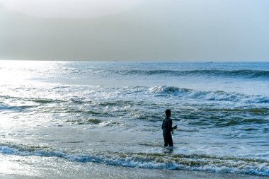 Chennai, Tamil Nadu, Hindistan - 02.07.2025: Okyanusta bir çocuk duruyor. Su mavi ve gökyüzü bulutlu. Chennai 'de.
