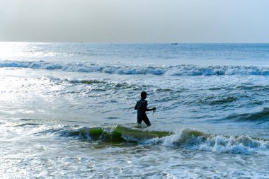 Chennai, Tamil Nadu, Hindistan - 02.07.2025: Okyanusta yüzen bir adam. Su mavi ve gökyüzü berrak. Chennai 'de.