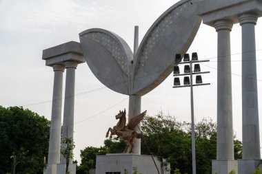Chennai, Tamil Nadu, Hindistan - 02.07.2025: Beyaz mermer kemer yolunun önünde büyük bir at heykeli ve kanatlı bir yaratık duruyor. Chennai 'de.