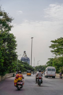 Chennai, Tamil Nadu, Hindistan - 02.07.2025: Motosikletli bir adam arkasında motosikletli bir kadınla caddede ilerliyor. Chennai 'de.