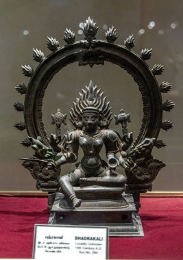 Chennai, Tamil Nadu, Hindistan - 02.07.2025: Kırmızı arka planda oturan bir kadın heykeli. Heykelin adı Bhadrakali. Chennai 'de.