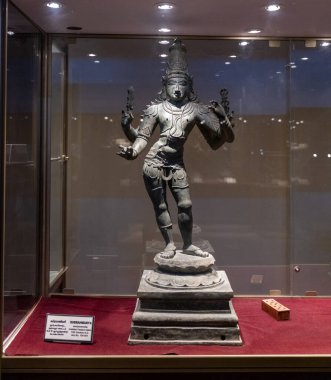 Chennai, Tamil Nadu, Hindistan - 02.07.2025: Silah tutan bir adamın heykeli. Heykel cam bir kutunun içinde. Dava kırmızı halıda. Chennai 'de.