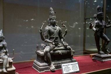 Chennai, Tamil Nadu, Hindistan - 02.07.2025: Bir heykelin üzerinde oturan bir adam heykeli. Heykel cam bir kutunun içinde. Chennai 'de.