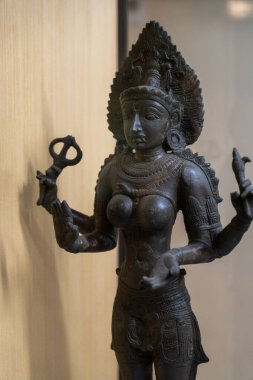 Chennai, Tamil Nadu, Hindistan - 02.07.2025: Makas tutan bir kadın heykeli. Heykel siyah ve altın işlemeli. Chennai 'de.