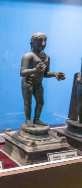 Chennai, Tamil Nadu, Hindistan - 02.07.2025: Kupa tutan bir adamın heykeli. Heykel cam bir kutunun içinde. Çanta masanın üstünde. Chennai 'de.