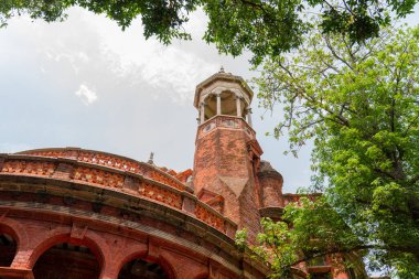 Chennai, Tamil Nadu, Hindistan - 02.07.2025: Önünde kulesi ve yeşil ağacı olan tuğla bir bina. Bina eski. Chennai 'de.