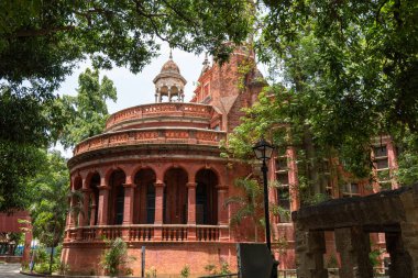 Chennai, Tamil Nadu, Hindistan - 02.07.2025: Yeşil çatılı kırmızı bir bina. Binanın büyük bir kemer yolu var. Chennai 'de.