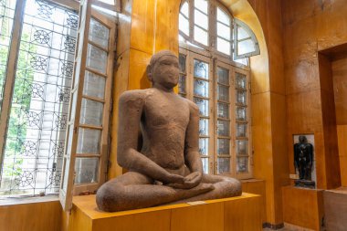 Chennai, Tamil Nadu, Hindistan - 02.07.2025: bacak bacak üstüne atmış bir adamın heykeli. Heykel pencereli bir odada. Chennai 'de.