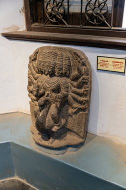 Chennai, Tamil Nadu, Hindistan - 02.07.2025: Dört kollu ve yüzlü bir adamın heykeli. Duvarın üstünde. Yanında bir tabela var. Chennai 'de.
