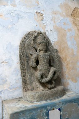 Chennai, Tamil Nadu, Hindistan - 02.07.2025: Yılan tutan bir adamın heykeli. Heykel taştan yapılmıştır. Duvara asılmış. Chennai 'de.