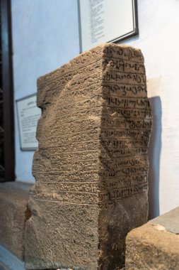 Chennai, Tamil Nadu, Hindistan - 02.07.2025: Üzerinde yazı olan bir taş levha. Yazı yabancı bir dilde yazılmış. Levha kahverengi. Chennai 'de.