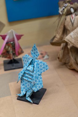 Chennai, Tamil Nadu, Hindistan - 02.07.2025: Mavi bir origami figürü stantta oturuyor. Arka planda başka origami figürleri de var. Chennai 'de.