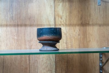 Chennai, Tamil Nadu, Hindistan - 02.07.2025: Siyah ve kahverengi bir seramik kase bir rafta duruyor. Raflar ahşaptan yapılmıştır. Chennai 'de.