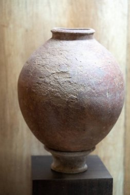 Chennai, Tamil Nadu, Hindistan - 02.07.2025: Ahşap bir kaidede kahverengi bir vazo bulunuyor. Vazo eski ve pürüzlü bir dokusu var. Chennai 'de.