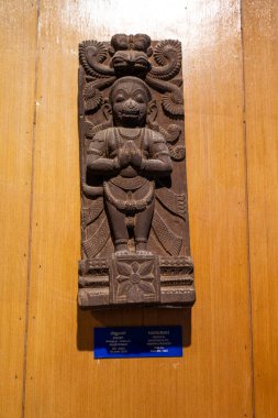 Chennai, Tamil Nadu, Hindistan - 02.07.2025: Ahşap bir yüzey üzerinde dua eden bir kişinin heykeli. Heykelin yanında mavi bir işaret var. Chennai 'de.