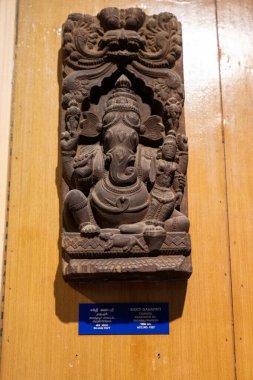 Chennai, Tamil Nadu, Hindistan - 02.07.2025: Büyük kafalı ve küçük vücutlu bir adam heykeli. Heykel ahşap bir duvarda. Chennai 'de.