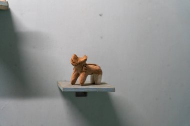 Chennai, Tamil Nadu, Hindistan - 02.07.2025: Bir köpeğin kahverengi heykeli bir rafta duruyor. Rafta bir duvar var. Köpek kilden yapılmıştır. Chennai 'de.