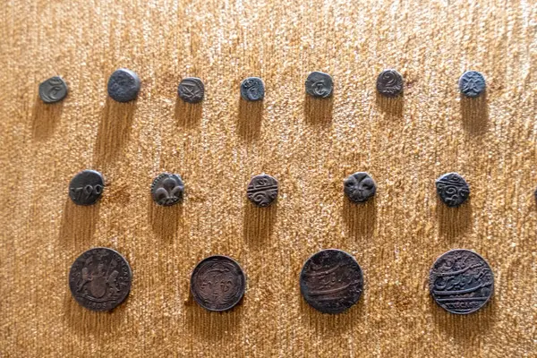 Chennai, Tamil Nadu, Hindistan - 02.07.2025: Eski madeni paraların bir koleksiyonu kahverengi bir kumaş üzerinde sergilenmektedir. Toplamda dokuz sikke var. Chennai 'de.