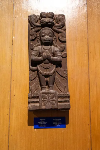 Chennai, Tamil Nadu, Hindistan - 02.07.2025: Ahşap bir yüzey üzerinde dua eden bir kişinin heykeli. Heykelin yanında mavi bir işaret var. Chennai 'de.