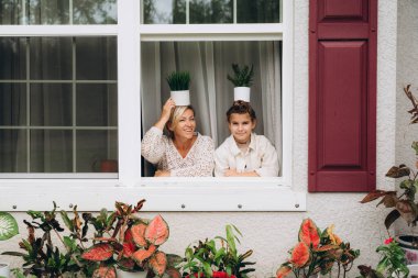 Gülümseyen anne ve kız pencereden bahçeye bakıyorlar..