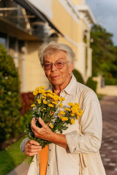 Sárga Virágokat Tartó Narancssárga Ruhában Elefántcsontszínű Ingben Mosolygó Idős Nők — Stock Fotó