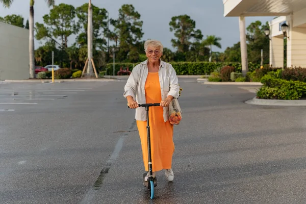 Portret Szczęśliwej Starszej Kobiety Pomarańczowej Sukience Pchającej Skuter Wysokiej Jakości — Zdjęcie stockowe