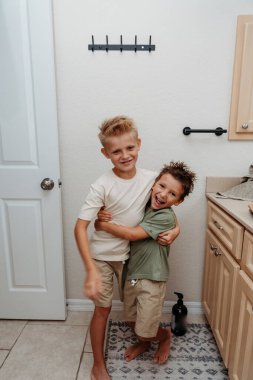 İki çocuk banyoda hazırlanıyor saçlarını tarayıp gülüyorlar. 