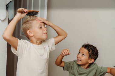 İki çocuk banyoda hazırlanıyor saçlarını tarayıp gülüyorlar. 