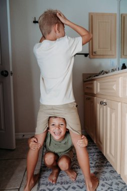 İki çocuk banyoda hazırlanıyor saçlarını tarayıp gülüyorlar. 