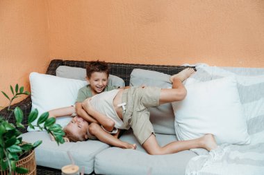 Çocuklar evin dışında oynuyorlar. Parlak güneş ışığı altında, neşeli bir atmosfer yaratıyorlar..