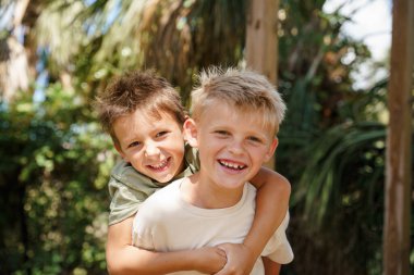 Çocuklar evin dışında oynuyorlar. Parlak güneş ışığı altında, neşeli bir atmosfer yaratıyorlar..