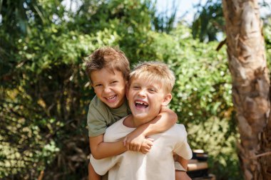 Çocuklar evin dışında oynuyorlar. Parlak güneş ışığı altında, neşeli bir atmosfer yaratıyorlar..