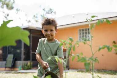 Bir çocuk bahçedeki bitkilerle ilgilenir. 