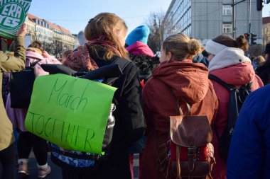 BERLIN, GERMANY - 19.01.2018: Two girls best friends fight and laugh marching together surrounded by feminist protesters in a protest against gender violence and in commemoration of March 8