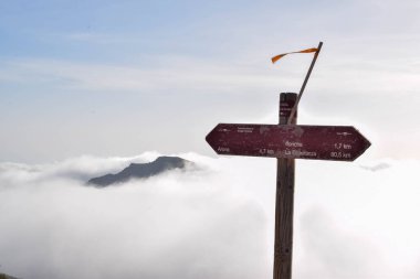 Track marker between the clouds up in the mountain. Trail hiking mark in the forest. Anaga - Chasna track, Teide National Park, Tenerife. Marking the tourist route painted.Touristic travel route sign.