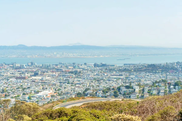 San Francisco şehir merkezindeki güneşli şehir ve okyanus ve dağ manzaralı mahalleler ile önplanda virajlı tepe ve yol ve tepe öğleyin gölgesiz.