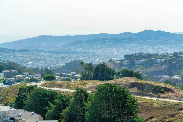 San Francisco California 'nın şehir merkezinde yuvarlanan kanyonlarla, ağaçlarla ve yeşilliklerle güneşli arka planda güneşli bir dağ yolu.