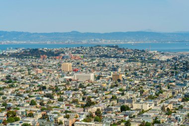 Mahalleleri ve dağları olan banliyö binaları olan ve gün ortasında okyanus geçmişi olan bir şehir. San Francisco şehir merkezinde bir sürü ev ve yapıya sahip geniş şehir manzarası..