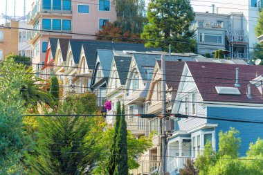 Modern mahallede San Francisco California 'da mavi bej rengi sarı ve beyaz evleri olan renkli evler veya görünür elektrik hatları olan evler. Gün ortasında, banliyöde ağaçlarla.