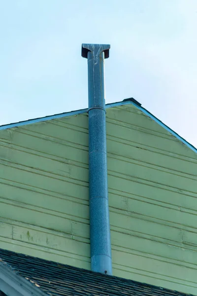 ベージュまたは白の横に灰色の金属煙突のパイプは 午後遅くに日陰で木材や木枠の家を平行にスレート 近代的な家の近所の青と白の薄曇りの空 — ストック写真