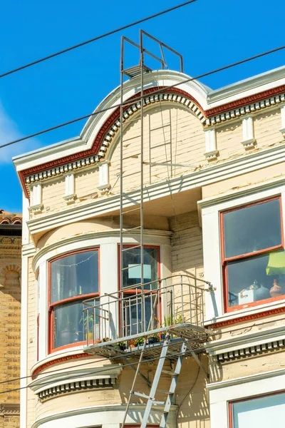 Beyaz Saray cephesi, bej renkli dekoratif aksanlı yangın merdiveni ve mavi gökyüzündeki platform. San Francisco 'da gün ortasında kırmızı pencereli ve telefon kablosu olan bulutlar..