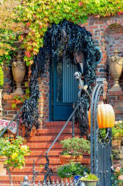 Dekoratif kırmızı tuğla merdiveni ve siyah el parmaklıkları olan San Francisco 'daki evin ön kapısı. Mahallede Cadılar Bayramı için cadılar bayramı süslemeleri var..