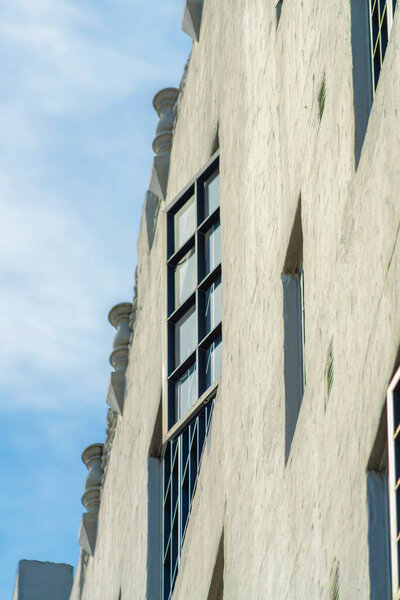 Close up of open window on exterior of modern apartment building with blue and white gradient sky in sun midday. Gray cement building in the city or in an urban area downtown.