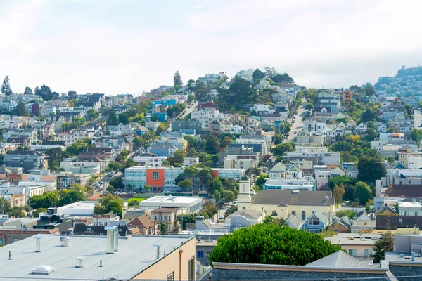 San Fransisco California 'nın varoşlarında sisli ve bulutlu arka planda geniş bir şehir manzarası. Öğleden sonra şehrin bir bölgesinde güneş, ağaçlar ve evlerle..