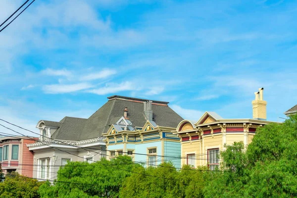 San Francisco California 'da renkli boyalı, ön bahçesinde yeşillik ve mavi gökyüzü arka planlı evler. Gün ortasında elektrik kabloları ve dekoratif cephe boyalarıyla evleri boyayarak..