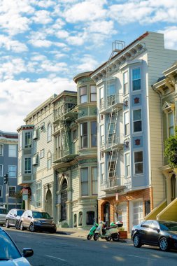 Öğleden sonra San Francisco şehir merkezinde cephesi olan modern dekoratif evler. Mavi ve bulutlu gökyüzü güneşli mahallede ya da şehirde arabalarla.