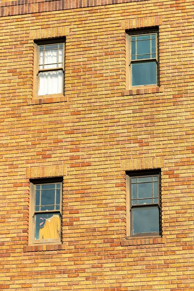 Close up view of four windows on the side of brick building facade in the midday sun in the city. Decorative brick exterior with hidden windows in the building in an urban area of the neighborhood.