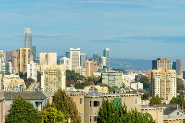 Şehir merkezindeki binalar ve akşam güneşinde ağaçlarla ve yapraklarla kaplı binalar ve dağlarla kaplı sisli mavi gökyüzü. İlkbaharın sonunda San Francisco 'da Kaliforniya' da.